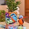 A colorful hand-painted paint-by-numbers planter featuring a blue kingfisher design, holding a green succulent plant.